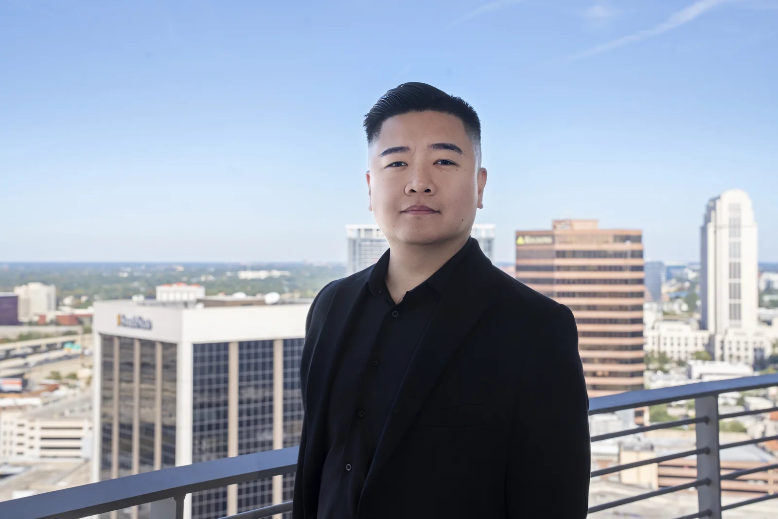 Thomas “Success” Wang — signature headshot in a black suit overlooking downtown Orlando